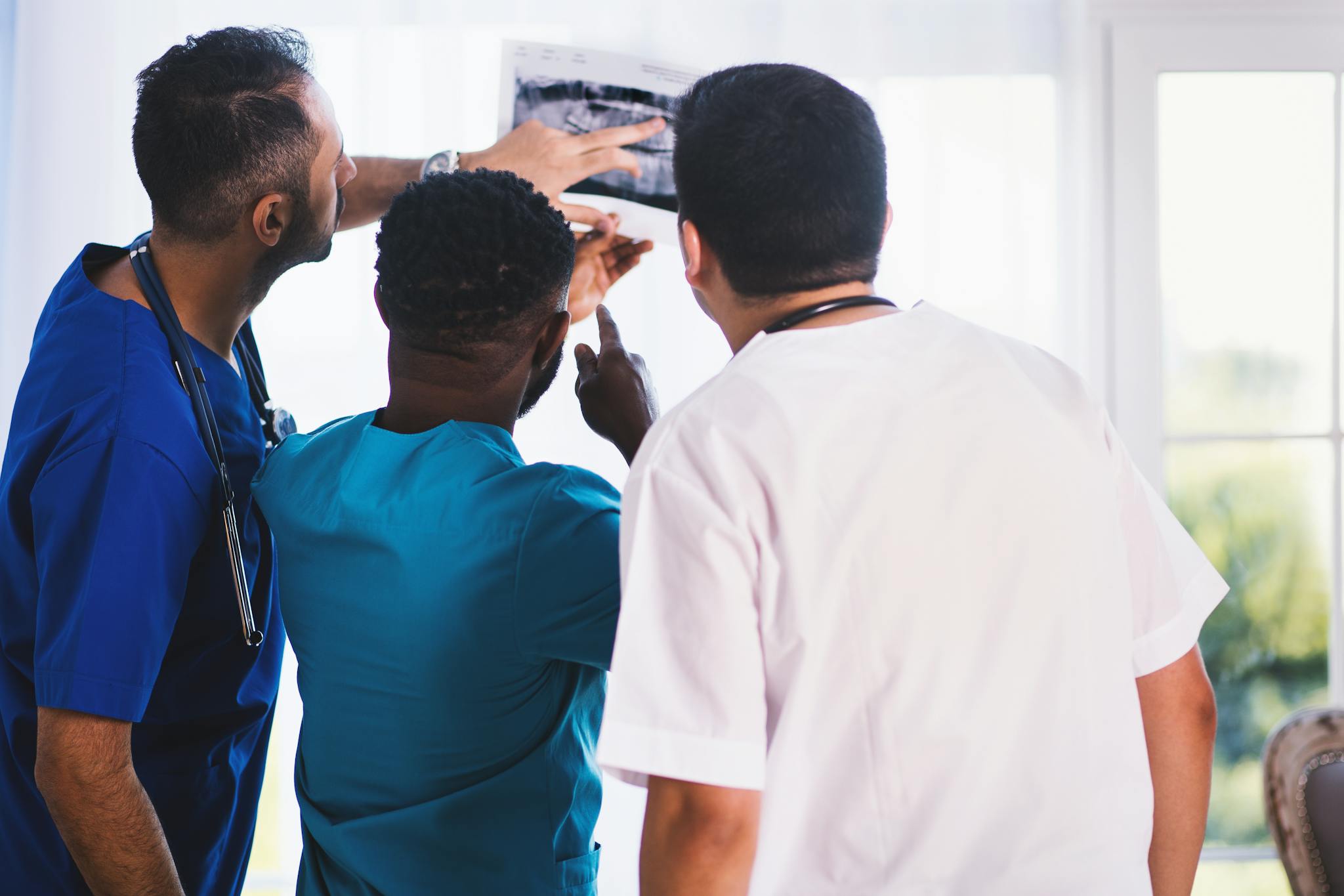Doctors collaboratively analyzing an X-ray in a clinical setting, showcasing teamwork and medical expertise.